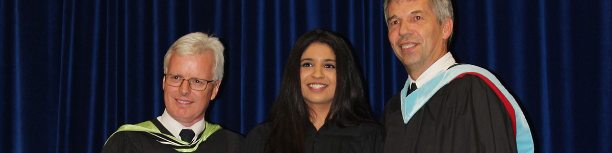 High School graduate on stage with Principal and Vice Principal